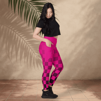 Woman wearing pink checkered leggings and black top against a beige wall.