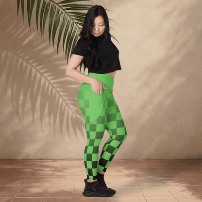 Person wearing green checkered leggings and black top against a beige wall with a plant.