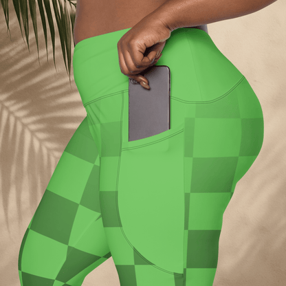 Green checkered leggings with a phone in pocket held by a hand against a beige background