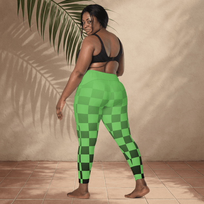 Person wearing green checkered leggings standing against a beige wall with a plant.