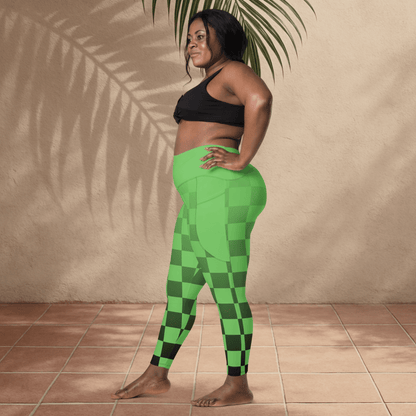Woman wearing green checkered leggings and black sports bra standing against a beige wall.
