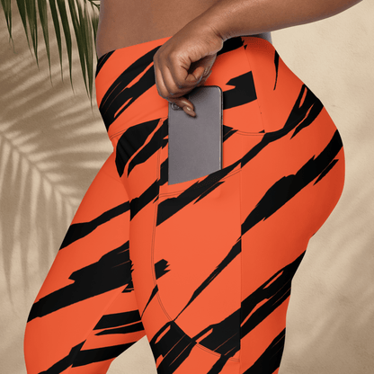 Person wearing orange leggings with black stripes holding a phone, against a beige background.