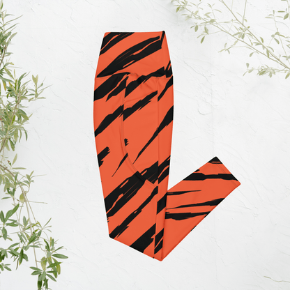 Orange and black striped leggings on a white background with green leaves.