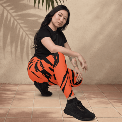Woman wearing black t-shirt and orange tiger stripe pants sitting on a tiled floor.