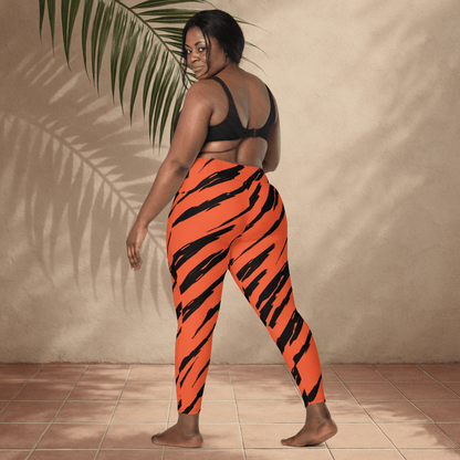 Person wearing orange and black tiger stripe pants standing against a beige wall.