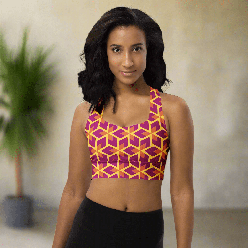 Woman wearing a geometric patterned sports bra and black leggings on a neutral background