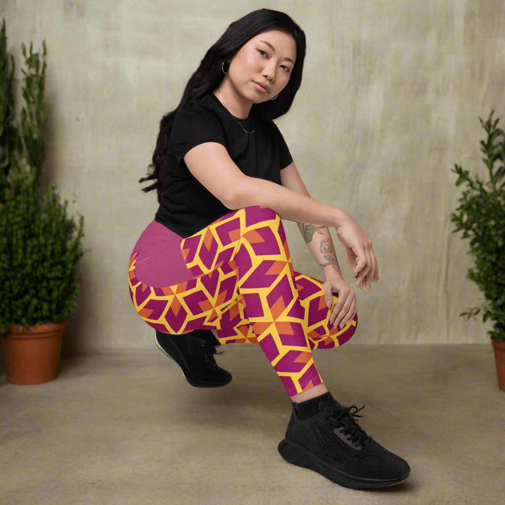 Person wearing a black t-shirt and colorful geometric-patterned pants on a neutral background