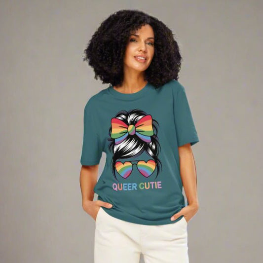 Woman wearing a teal t-shirt with a colorful graphic and text, standing against a white background