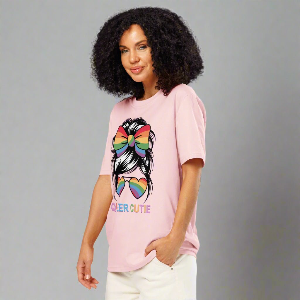 Person wearing a pink t-shirt with a rainbow design and "QUEER CUTIE" on a white background