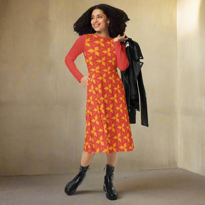 Woman wearing a red dress with yellow pattern, holding a black jacket against a beige wall.