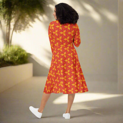 Woman wearing a red and yellow patterned dress on a neutral background 