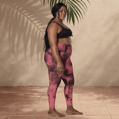 Woman wearing pink and black tie-dye leggings and black top standing against a beige wall.