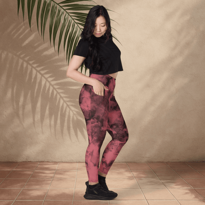 Woman wearing pink and black patterned leggings with a black top against a beige wall.