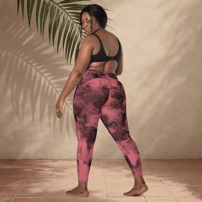 Person wearing pink and black tie-dye leggings standing against a beige wall with a plant leaf.