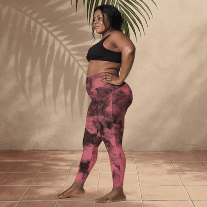 Woman wearing a black sports bra and pink tie-dye leggings standing against a beige wall.