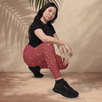 Woman wearing maroon leggings with gold patterns and black shoes, sitting on a tiled floor.