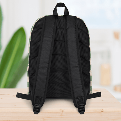 Backside of a backpack on a wooden surface with a blurred plant and light background