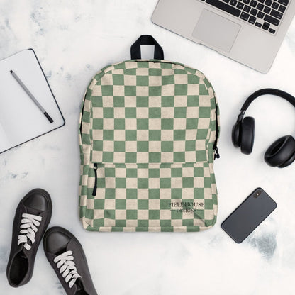 Checkered backpack on a marble surface with a laptop, headphones, and shoes.
