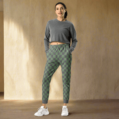 Woman wearing a gray crop top and green checkered pants against a beige wall.