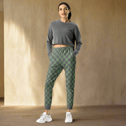 Woman wearing a gray crop top and green checkered pants against a beige wall.