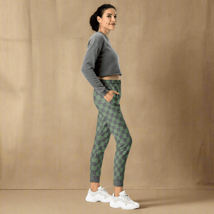 Woman wearing a gray sweatshirt and green checkered pants on a neutral background