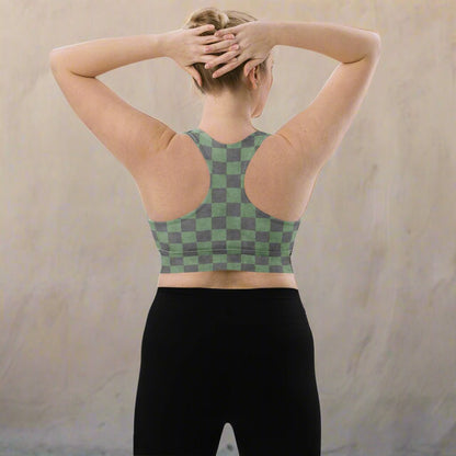 Person wearing a green and gray checkered sports bra and black leggings against a beige background