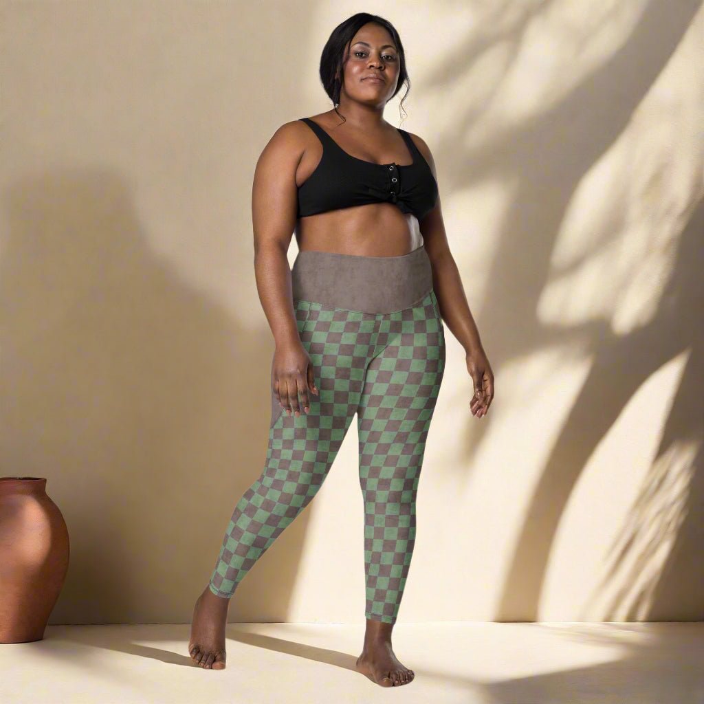 Woman wearing a black sports bra and green checkered leggings standing against a neutral background.