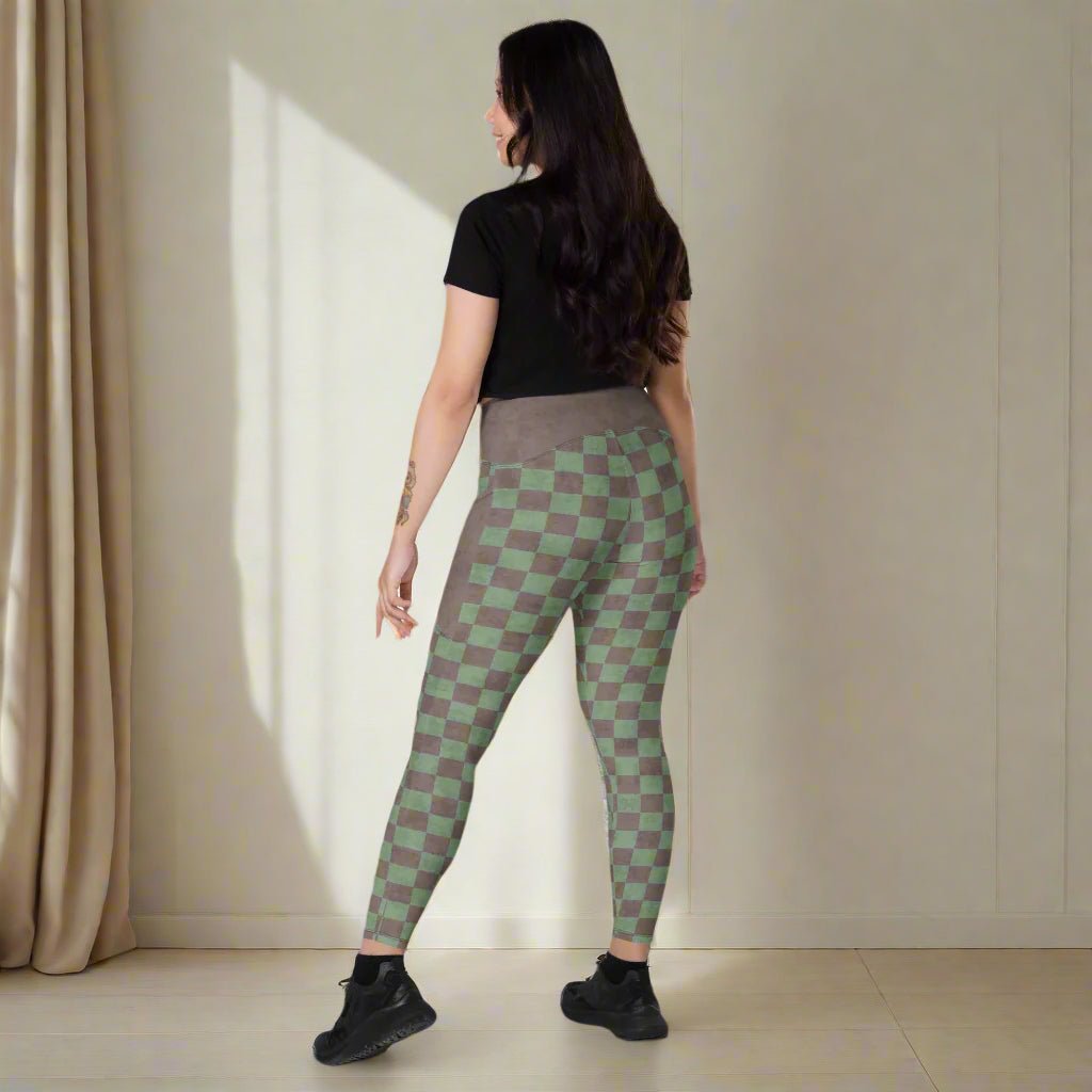 Woman wearing green and brown checkered leggings against a wall.