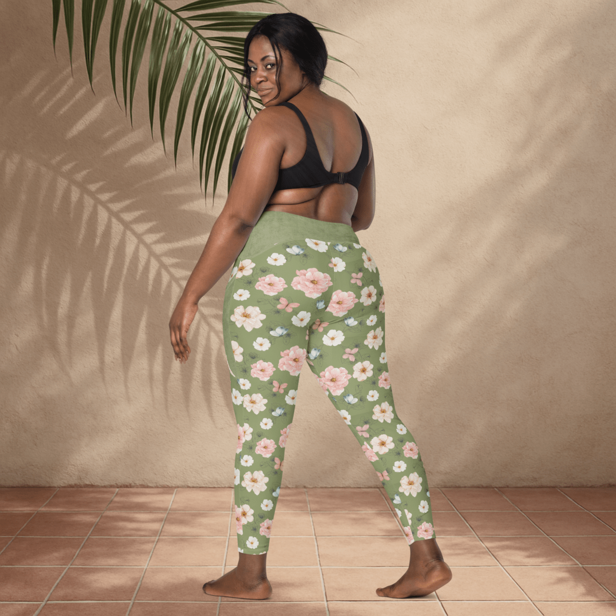 Woman wearing green floral leggings against a beige wall.
