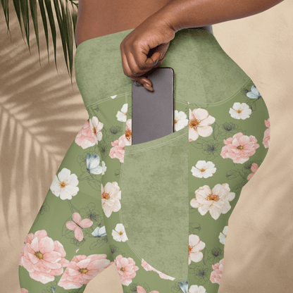 Green floral leggings with a pocket holding a phone, against a beige background.