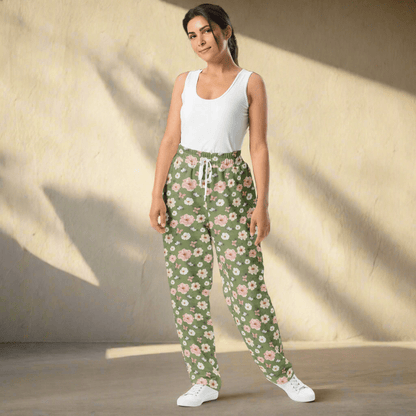 Woman wearing a white tank top and green floral pants on a neutral background