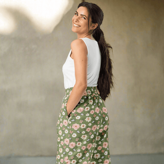 Woman wearing a white top and green floral joggers against a neutral background
