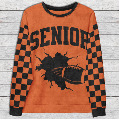 Orange sweatshirt with 'SENIOR' and football graphic on a wooden surface