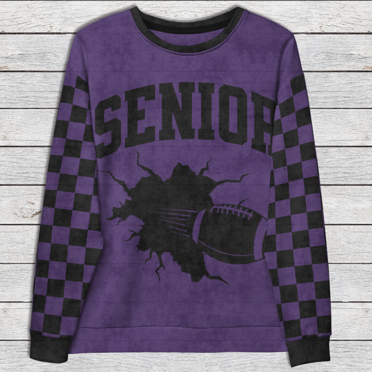 Purple sweatshirt with 'SENIOR' and football graphic on a wooden surface