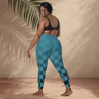Person wearing blue checkered leggings standing against a beige wall with a plant.