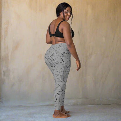 Woman wearing gray patterned leggings and black sports bra on a beige background