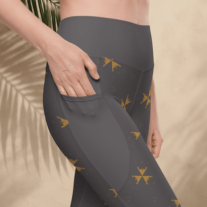 Dark gray leggings with gold patterns worn by a person against a beige background