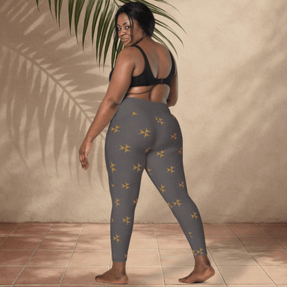 Woman wearing gray leggings with yellow star patterns against a beige wall.