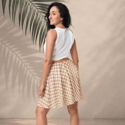 Woman wearing a white sleeveless top and checkered skirt standing against a beige wall with a palm leaf.