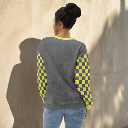 Person wearing a gray sweater with checkered sleeves against a textured wall.