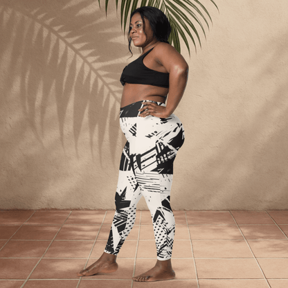 Woman wearing black and white patterned leggings and sports bra standing against a beige wall.