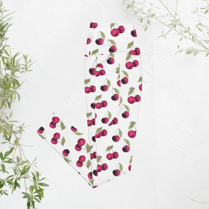 White leggings with red cherry pattern on a white background with green leaves.