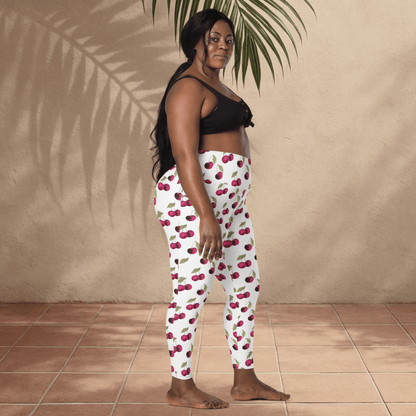Woman wearing cherry-patterned leggings standing against a beige wall.