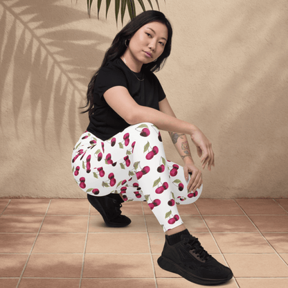 Woman wearing white pants with red cherry pattern and black shoes on a beige background