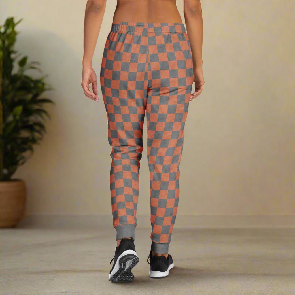 Person wearing terracotta and gray checkered sweatpants on a neutral background