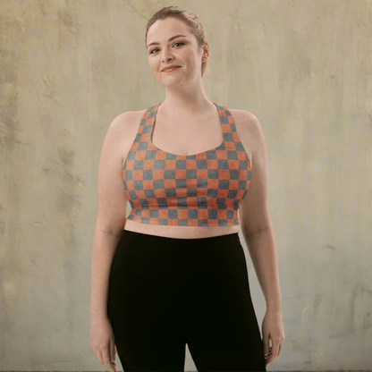 Woman wearing a checkered sports bra and black leggings against a textured beige wall.