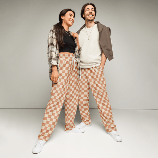Two people wearing matching checkered pants against a plain background