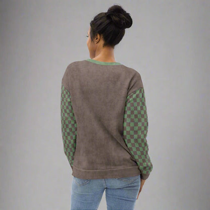 Person wearing a gray sweatshirt with green checkered sleeves on a gray background