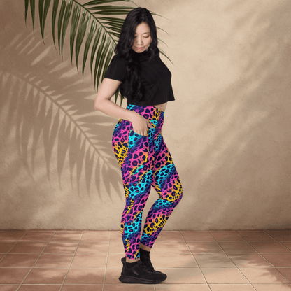 Woman wearing colorful leopard print pants and a black top against a beige wall.