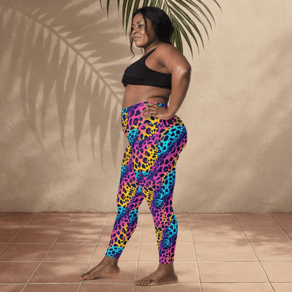 Person wearing colorful leopard print leggings and black sports bra against a beige wall.